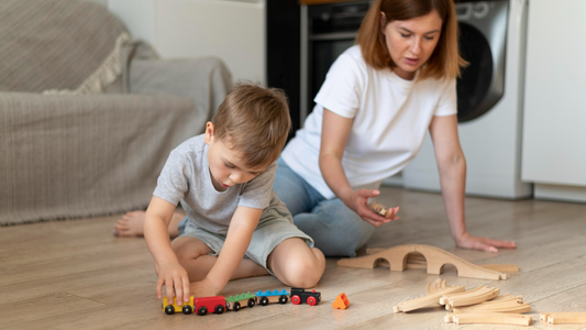 Mother watching her son play with wooden train set.