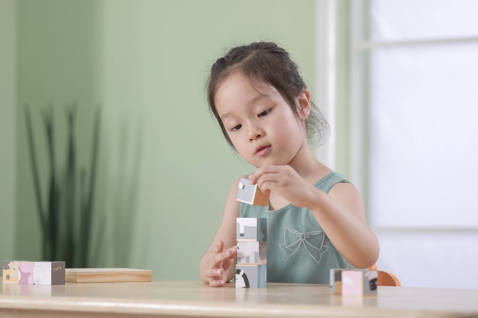 A child playing with a 6-sided wooden toy puzzle made by PolarB, featuring nine cube blocks assembled in a wooden tray. The blocks display a cheerful cartoon polar bear on a striped background, forming one of the six potential puzzle images. The wooden tray sits behind the assembled cubes, with other puzzle designs visible on the sides.