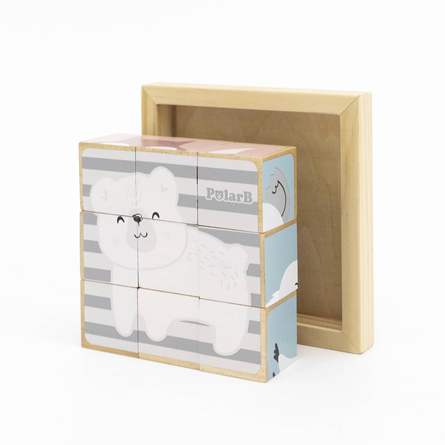 A 6-sided wooden toy puzzle made by PolarB, featuring nine cube blocks assembled in a wooden tray. The blocks display a cheerful cartoon polar bear on a striped background, forming one of the six potential puzzle images. The wooden tray sits behind the assembled cubes, with other puzzle designs visible on the sides.